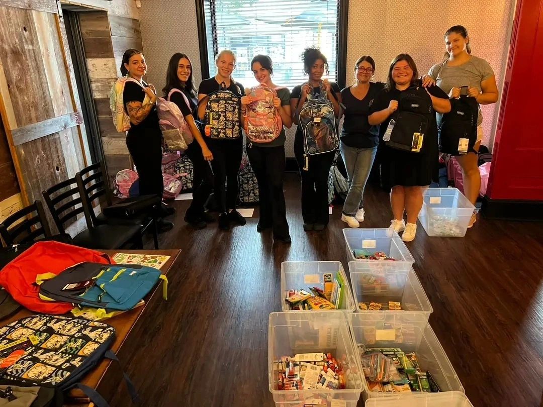 Volunteers holding packed backpacks at Darby Road Pub